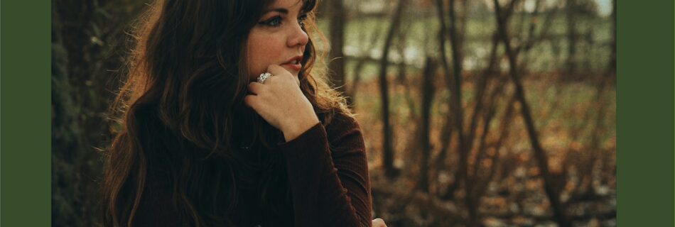Single cover artwork for Thicket of lies with a photo of YENI dressed in a dark brown shirt, looking to the side with the hand under her chin. the surrounding area is green and above the photo is the YENI logo in a darker shade of green and below is the text Thicket of Lies in a cursive white font